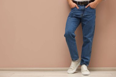 Bej duvarın yanında şık kotlu bir adam, yakın plan. Metin için boşluk