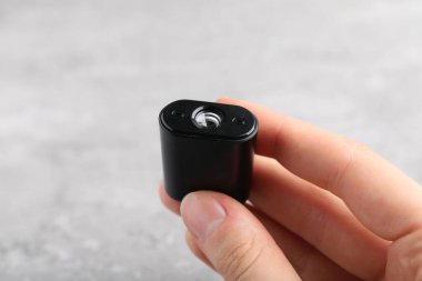 Açık gri masada elinde modern casus kamerası olan bir kadın. Yakın plan.