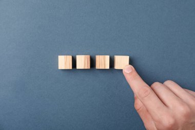 Gri arka planda tahta küpleri olan adam, üst manzara.