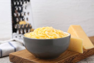 Gri masada rendelenmiş peynir parçaları, yakın plan.