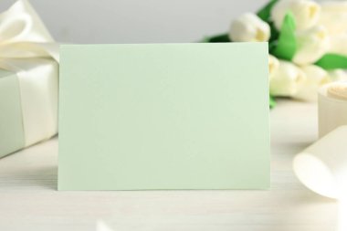 Boş kart, hediye ve çiçekler beyaz ahşap masada, yakın plan. Tasarım için model