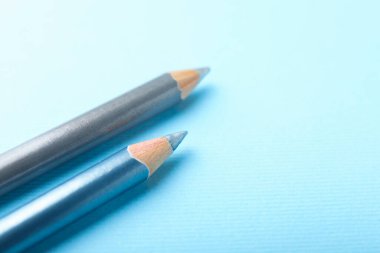 Açık mavi arka planda göz kalemleri, yakın plan. Metin için boşluk