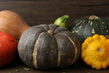 Bir sürü taze balkabağı, tohum ve diğer sebzeler ahşap masada, yakın plan.