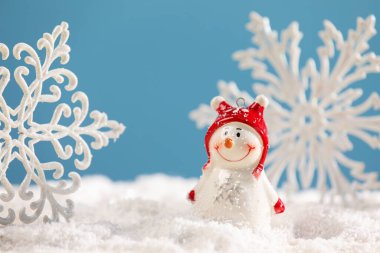 Güzel dekoratif kardan adam ve kar taneleri suni kar üzerinde açık mavi arka planda, yakın plan