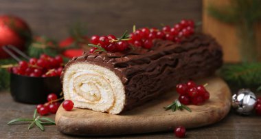 Lezzetli Noel kütüğü (geleneksel Noel pastası) ahşap masa üzerinde kırmızı frenk üzümü, yakın plan