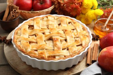 Lezzetli ev yapımı turta, taze elmalar, bal ve çiçekler ahşap masada, yakın plan.