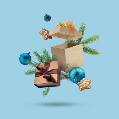 Noel ya da yeni yıl kutlaması. Hediye kutuları, kurabiyeler ve açık mavi arka planda uçan şenlikli dekorlar.