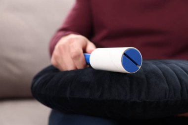 Kanepede pamuklu bezle yastığı temizleyen adam, yakın plan.