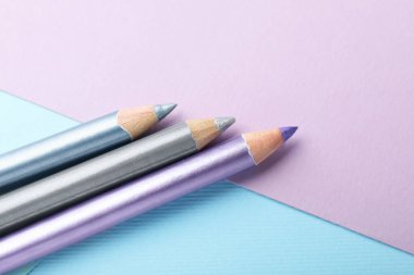 Renkli arka planda renkli göz kalemleri, düz yatış. Metin için boşluk