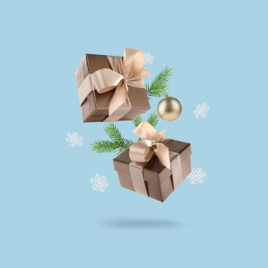 Noel ya da yeni yıl kutlaması. Hediye kutuları ve şenlikli dekorlar açık mavi arka planda havada uçuşuyor.