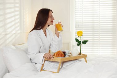 Kadın yatakta nefis bir kahvaltı yapıyor. Otel oda servisi.