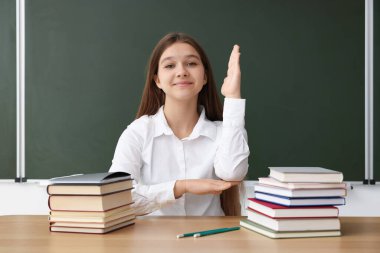 Okula dönelim. Öğrenci ahşap masada karatahtaya el kaldırıyor.