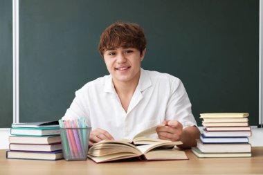 Okula dönelim. Öğrenci ahşap masada karatahtaya karşı çalışıyor.