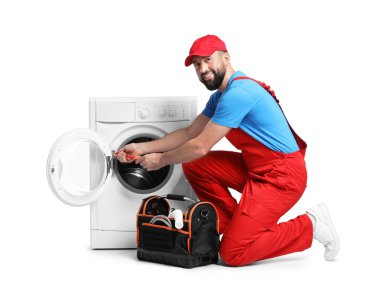 Beyaz arka planda bozuk çamaşır makinesini tamir eden profesyonel bir tamirci