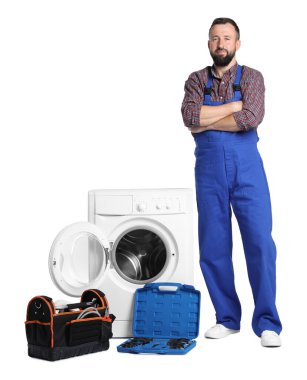 Beyaz arka planda bozuk çamaşır makinesinin yanında aletleri olan profesyonel bir tamirci.