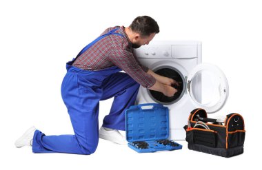 Beyaz arka planda bozuk çamaşır makinesini tamir eden profesyonel bir tamirci