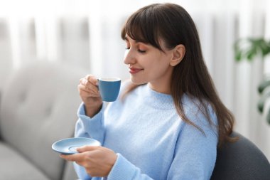 Evdeki kanepede kahve molası veren güzel kadın.