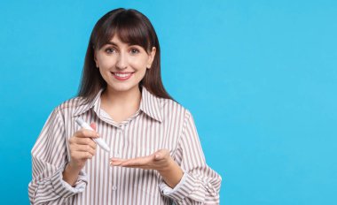 Diyabet testi. Kan şekeri seviyesini açık mavi arkaplandaki tükenmez kalemle kontrol eden kadın, metin için boşluk