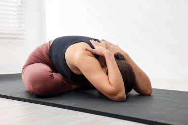 Spor kıyafetli kadın içeride yoga yapıyor.
