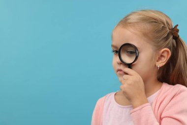 Açık mavi arka planda büyüteç takan küçük bir kız. Metin için boşluk