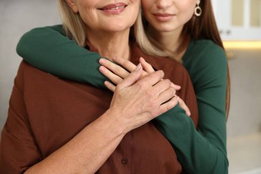 Kızı mutfakta annesine sarılıyor, yakın plan.