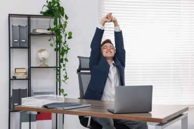 Genç işadamı kollarını uzatıp, masada oturuyor.