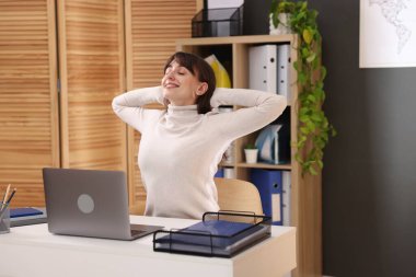 Genç iş kadını ofiste sırtını esnetiyor.