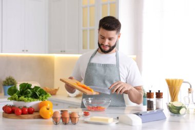 Genç adam mutfaktaki masada yemek pişiriyor.