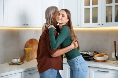 Anne ve kızı mutfakta sarılıyor. Aile bağı