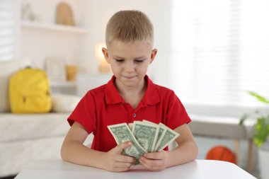 Beyaz masada cep harçlığı tutan küçük çocuk.