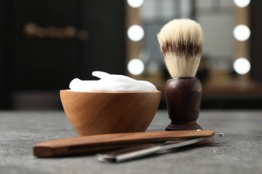 Traş fırçası, köpük ve jilet berber dükkanında gri desenli masada, yakın plan.