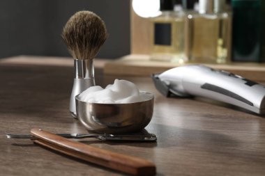 Traş fırçası, köpük, jilet ve saç makası berber dükkanındaki ahşap masada, yakın plan.
