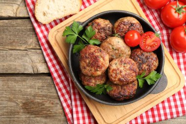 Maydanozlu leziz köfteler, domatesler ve ahşap masada ekmek.