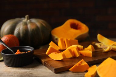 Taze balkabakları, tohumlar ve kabuklar tuğla duvara karşı ahşap masada, yakın plan.