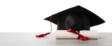Mezuniyet şapkası ve diploması beyaz arka plana karşı ahşap masada.