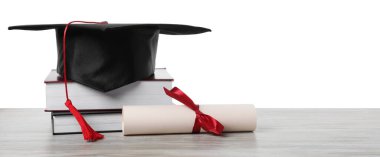 Mezuniyet şapkası, diploma ve beyaz arka plana karşı ahşap masa üzerindeki kitaplar.