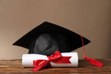 Mezuniyet şapkası ve diploması ahşap masada, yakın plan.