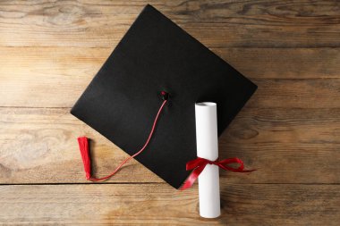 Mezuniyet şapkası ve diploması ahşap masada, düz yatıyordu.