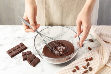 Beyaz masada erimiş çikolatayı karıştıran kadın, yakın plan.