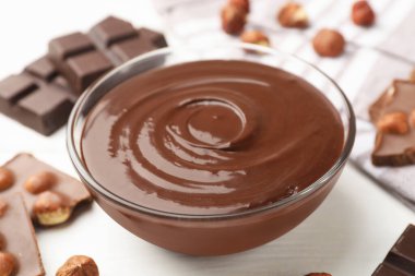 Erimiş çikolata ve fındıklı beyaz tahta masa, yakın plan.