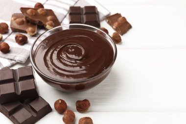 Erimiş çikolata ve fındıklı beyaz ahşap masa, yakın plan. Metin için boşluk