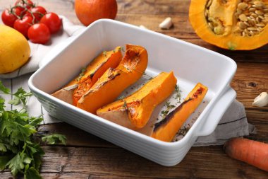 Baked pumpkin and ingredients on wooden table, closeup