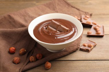 Erimiş çikolata ve fındıklı ahşap masa, yakın plan.