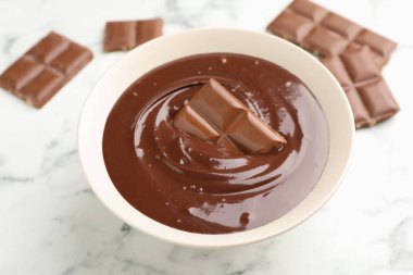 Erimiş çikolata ve parçalar beyaz mermer masada, yakın plan.