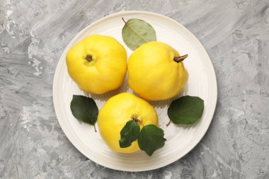 Gri desenli masa üzerinde taze, olgun ayva yaprakları.