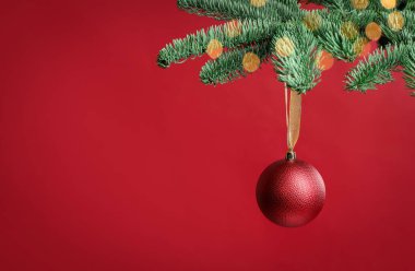 Kırmızı arka planda köknar dalında asılı duran güzel Noel balosu. Metin için boşluk