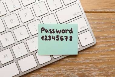 Tahta masa üzerinde parola ve bilgisayar klavyeli kağıt not, üst görünüm