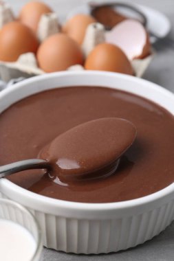Tabakta sıvı çikolata hamuru ve gri masada malzemeler, yakın plan.