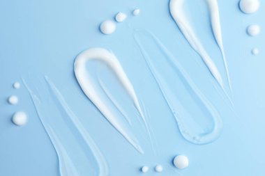 Açık mavi zemin üzerinde farklı kozmetik ürünleri örnekleri, düz yatıyordu