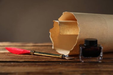 Eski kağıt parşömen, dolmakalem ve tahta masa üzerindeki mürekkep hokkası, yakın plan.